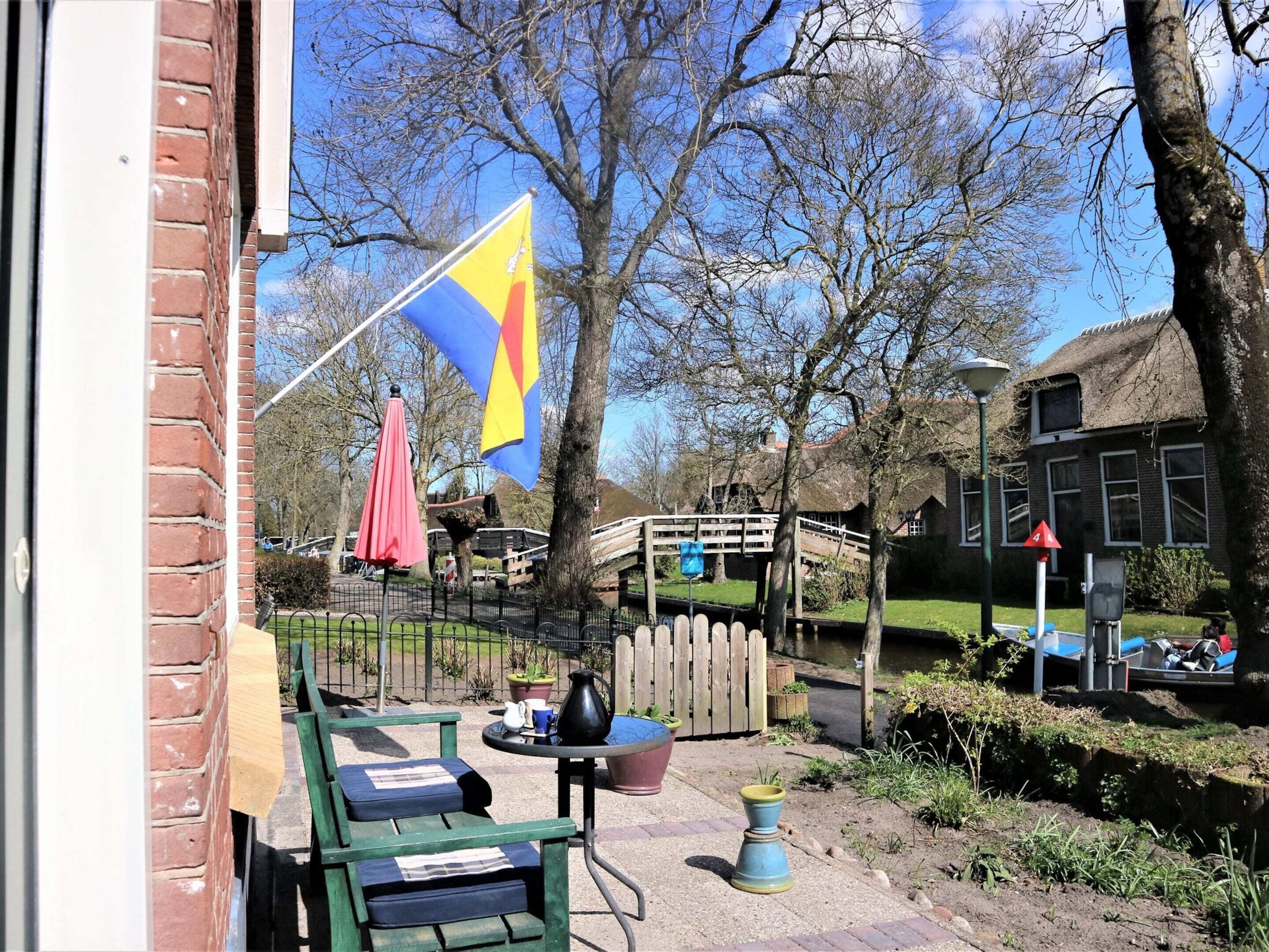 A courtyard with a flag, outdoor seating, and a wooden bridge over a water feature.