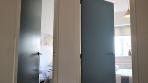 Una habitación con una cama, una ventana y una puerta que da a otra habitación.