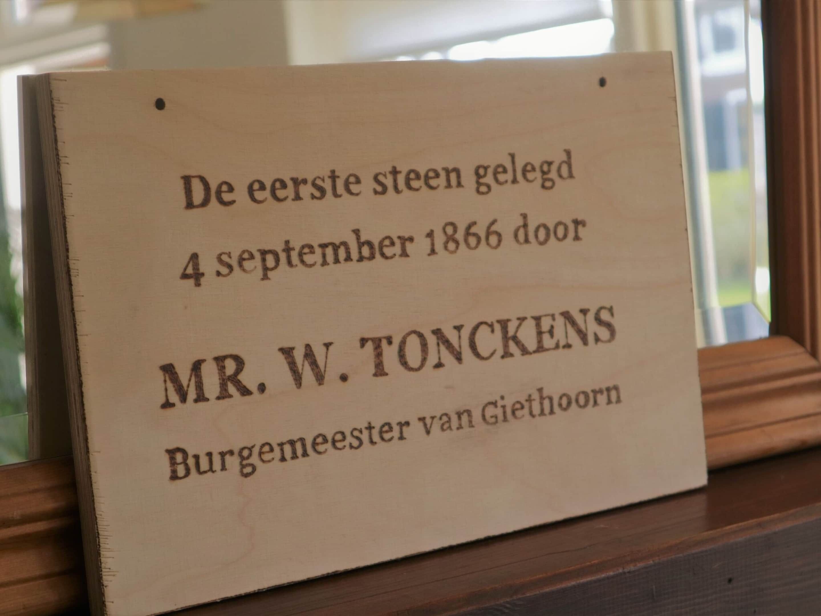 Une plaque en bois, portant une inscription en néerlandais, commémore un événement historique lié à M. W. Tonckens, maire de Giethoorn, survenu le 4 septembre 1866.