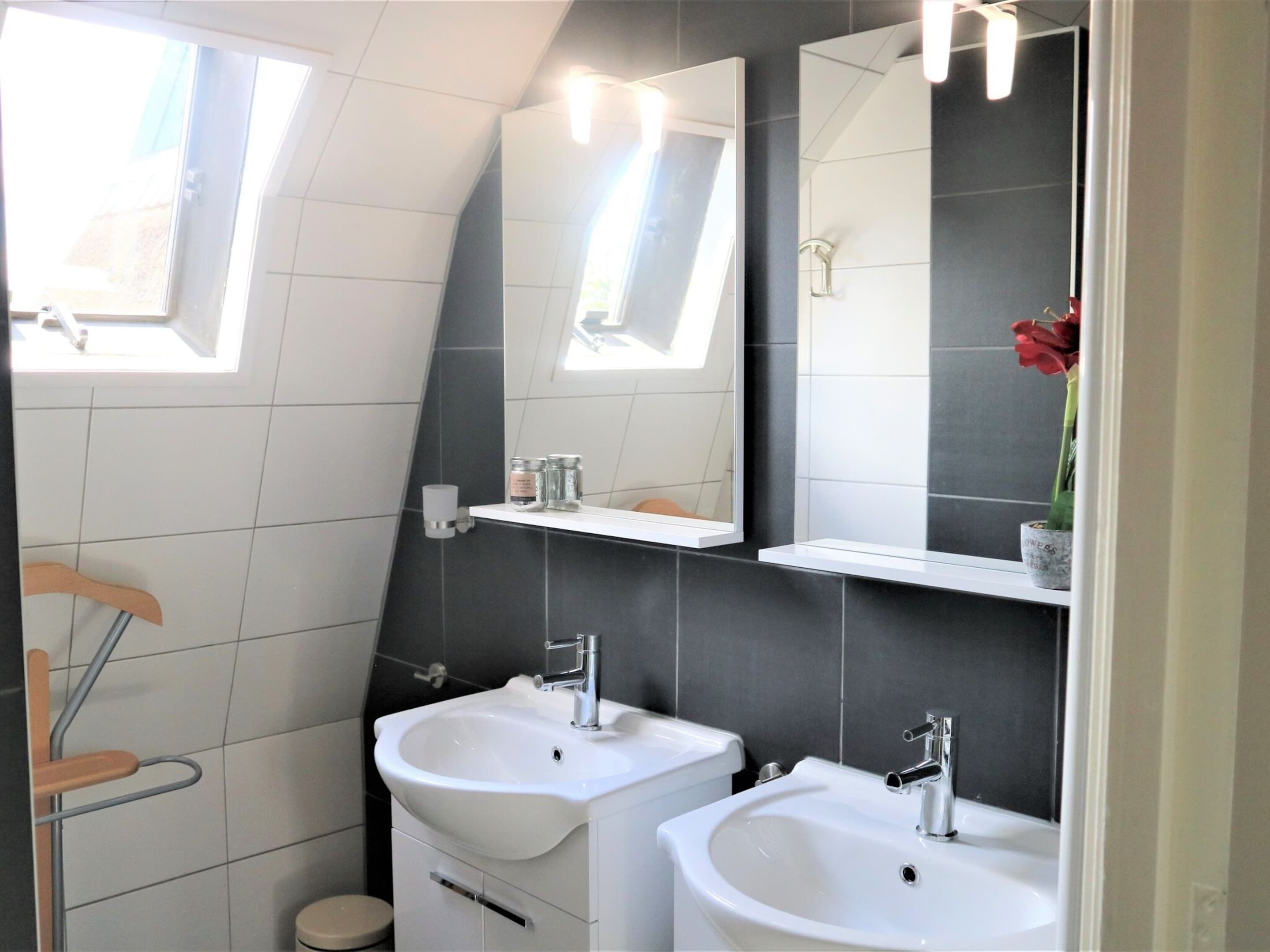 A modern bathroom with two sinks, a mirror, and a window.