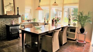 Un comedor con una mesa de madera, sillas de mimbre, una lámpara colgante y una planta en maceta.