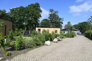 A paved courtyard with a wooden building, a small yellow structure, and a truck.