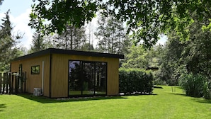 A modern, single-story building with large glass windows, surrounded by a well-maintained lawn and dense trees. - Pleasant Nature Lodge in Dalerveen (Dalerveen)