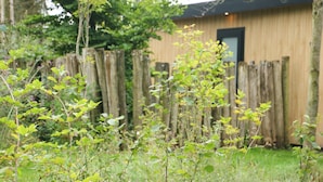 A wooden building with a dark door, surrounded by a wooden fence and greenery. - Pleasant Nature Lodge in Dalerveen (Dalerveen)