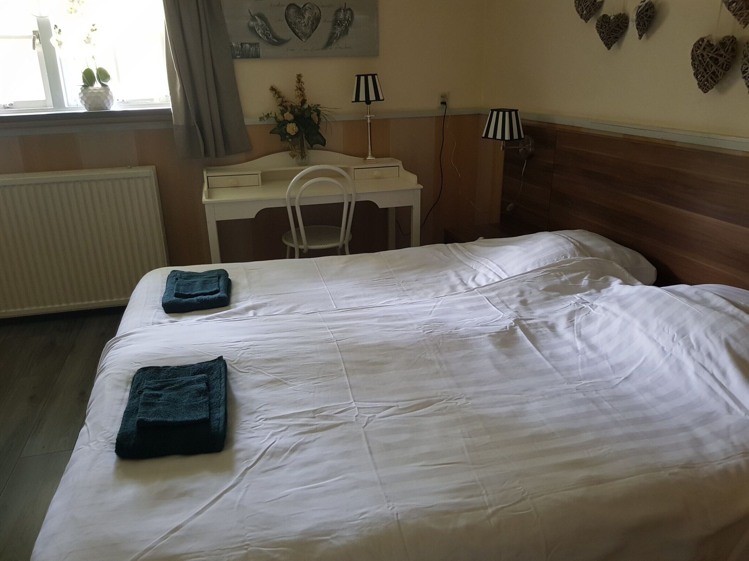 A bedroom with a large bed, a desk, and a chair.