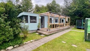 A mobile home with a porch and a trampoline in the yard. - Lovely Chalet in De Pol With Garden (De Pol)