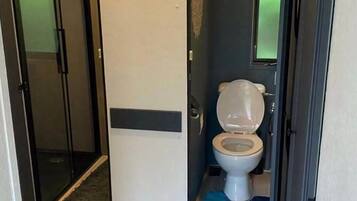 A bathroom with a toilet, a shower door, and a rug.