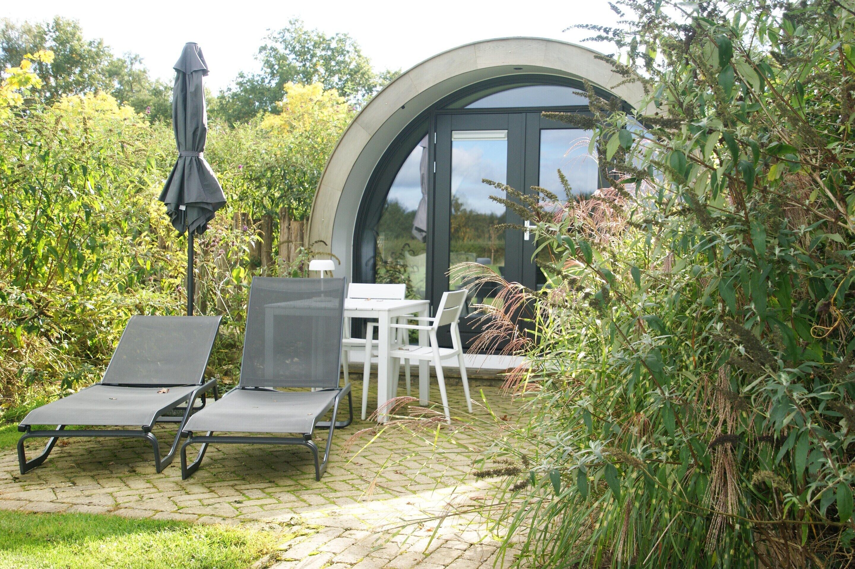 A patio with two lounge chairs, a table, and an umbrella.