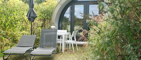 A patio with two lounge chairs, a table, and an umbrella.