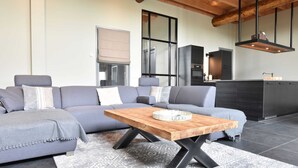 Una sala moderna con un sofá seccional gris, una mesa de centro de madera y una alfombra estampada.