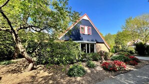 A house with a gabled roof, a front porch, and a garden with red flowers. - Holiday Home Buitenplaats Berg With 5 Rooms (Lemele)