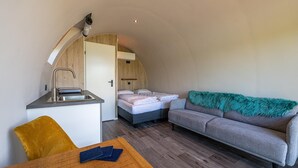 A compact room with a kitchenette, a bed, a sofa, and a dining table. - Couple Retreat at Unique Nature Lodge (Dalerveen)