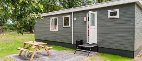 A small, single-story mobile home with a picnic table and a small porch.