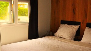 A bedroom with a bed, a window, and a wooden wall. - Peaceful Chalet Close to Norg (Haulerwijk)