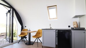 A compact kitchen with a sink, a small refrigerator, and two chairs. - Unique Nature Lodge With Terrace Garden (Dalerveen)
