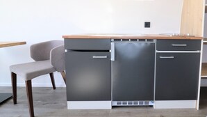 A compact kitchenette with a grey cabinet, a wooden countertop, and a grey chair. - Unique Nature Lodge With Terrace Garden (Dalerveen)