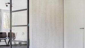 A modern room with a glass door leading to a seating area with chairs and a table. - Lakeside Luxury; Sauna & Hot Tub (Noordwolde)