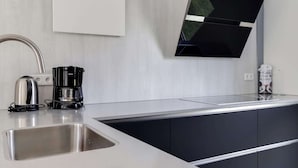 A modern kitchen with a stainless steel sink, a coffee maker, and a wall-mounted TV. - Lakeside Luxury; Sauna & Hot Tub (Noordwolde)