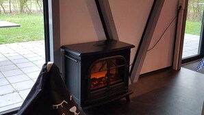 A modern interior with a black wood-burning stove, a glass door leading outside, and a wall with the word "Beautiful" written on it. - Spacious Holiday Home in Noordwolde With Garden (Noordwolde)