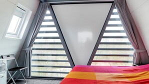 A room with a bed, a desk, and a chair. There is a window with blinds and curtains. - Spacious Holiday Home in Noordwolde With Garden (Noordwolde)