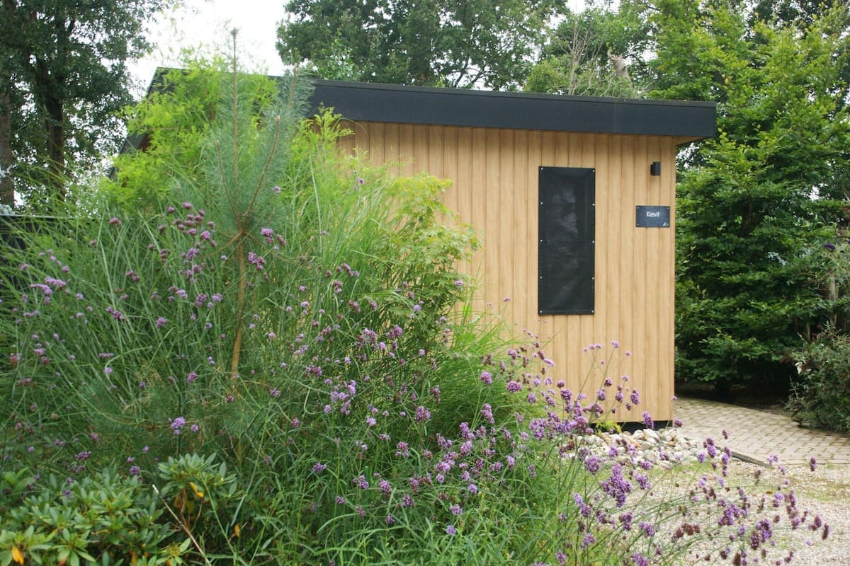 Una pequeña estructura de madera con una puerta negra y un letrero que dice 'Kleivf'.