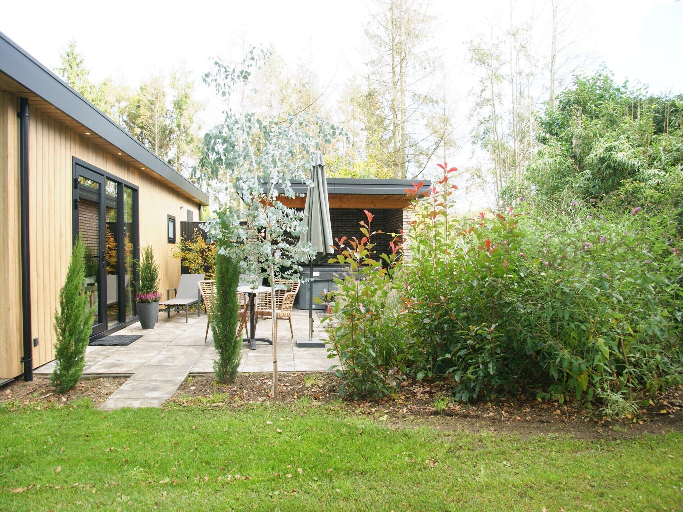 Een moderne patio met tuinmeubilair, een kleine boom en een tuin.
