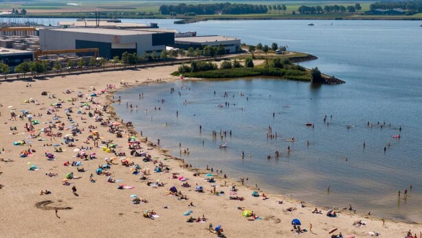 A beach with people sunbathing and swimming, surrounded by buildings and a river. - Fantastic Chalet Near Open Waterways, hot tub (Rutten)