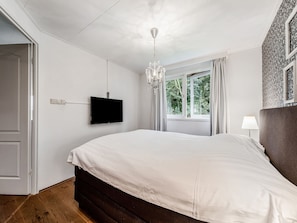 A bedroom with a bed, a TV mounted on the wall, a window with curtains, and a chandelier. - Fantastic Chalet Near Open Waterways, hot tub (Rutten)