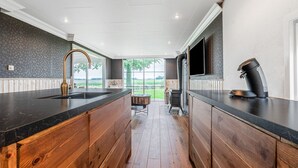 A modern kitchen with a large island, a built-in stove, and a large window offering a view of the outdoors. - Fantastic Chalet Near Open Waterways, hot tub (Rutten)