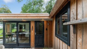 A wooden exterior with a sliding glass door leading to an interior with a dining area. - Fantastic Chalet Near Open Waterways, hot tub (Rutten)