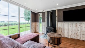 A modern living room with a large window, a fireplace, and a flat-screen TV. - Fantastic Chalet Near Open Waterways, hot tub (Rutten)