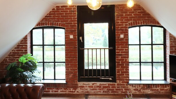 A loft-style room with exposed brick walls, large windows, and a black door. - Shed 57b in an old Flour Mill in Haulerwijk (Haulerwijk)
