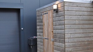 A wooden shed with a metal door and a small light fixture above it. - Shed 57b in an old Flour Mill in Haulerwijk (Haulerwijk)