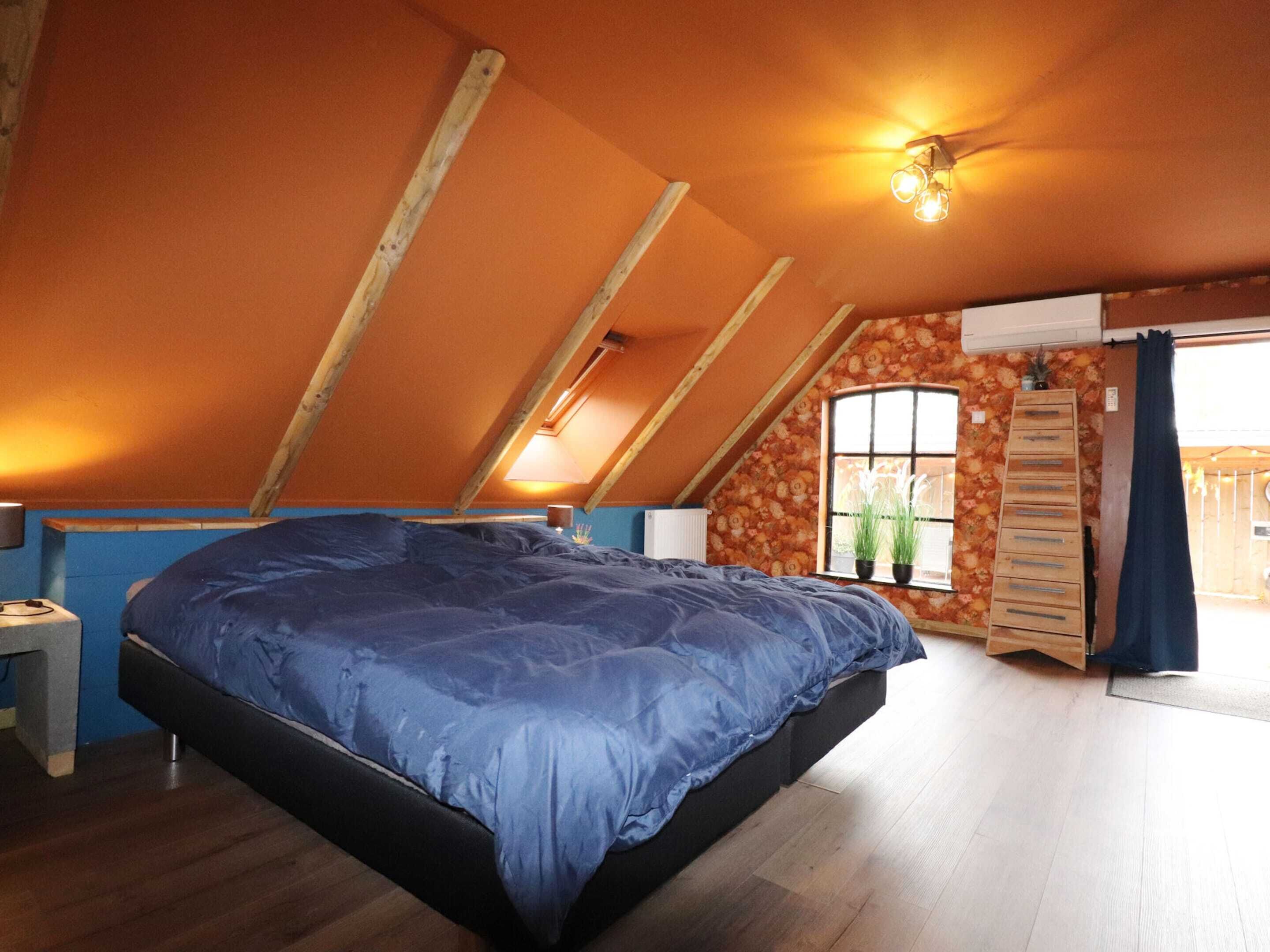 A bedroom with a sloped ceiling, a bed, a window with a view, and a ladder against the wall.