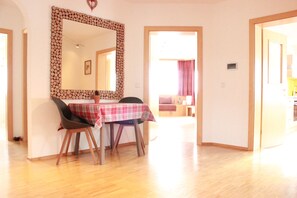 Un comedor con una mesa dispuesta para dos, un espejo grande con marco de madera, y piso de madera.