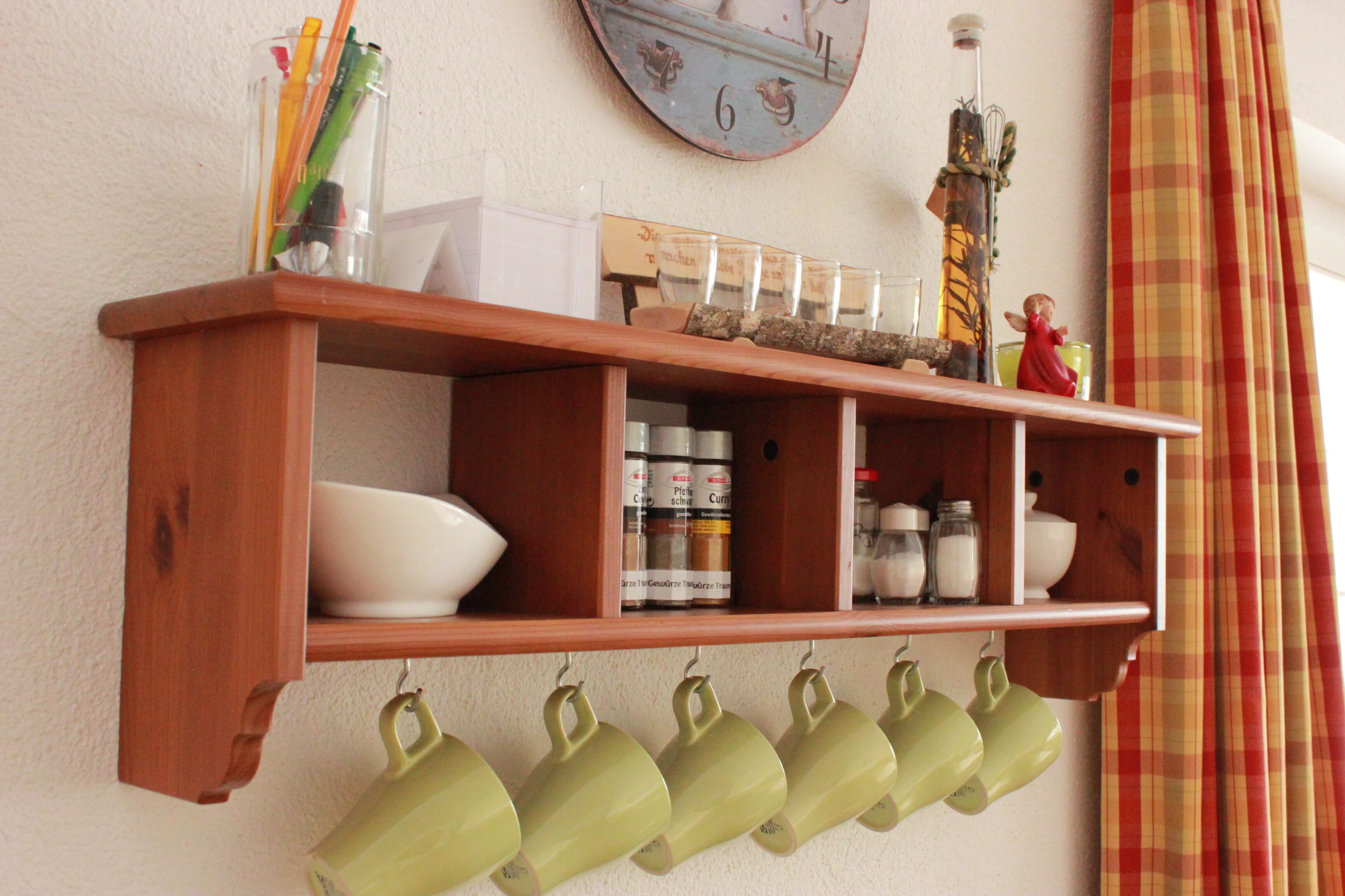 Une étagère en bois sur laquelle sont disposés divers objets de cuisine, notamment des bols, des bocaux et une horloge.