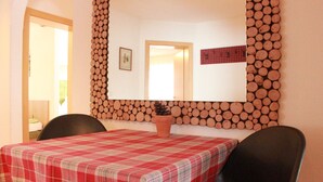 A dining area with a checkered tablecloth, a potted plant, and a wall-mounted log display. - Summer dream vacation apartment in the Zillertal with magnificent views (Schwendau)
