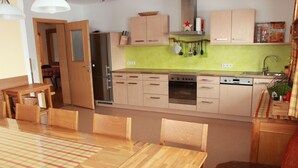 A compact kitchen with wooden cabinets, a refrigerator, an oven, and a dishwasher. - Summer dream vacation apartment in the Zillertal with magnificent views (Schwendau)