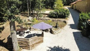 A rustic outdoor seating area with a table and chairs, surrounded by trees and a stone wall. - La Chenaie ( 2C ) (Sorges et Ligueux en Périgord)