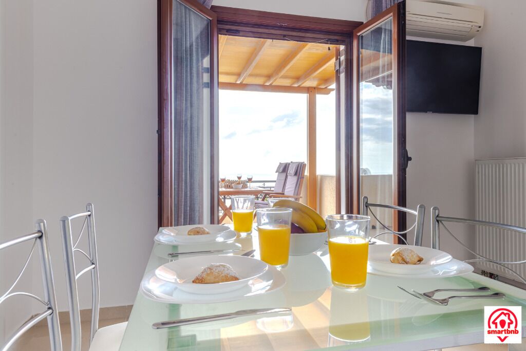 A breakfast table with plates, glasses of orange juice, and a bowl of fruit.