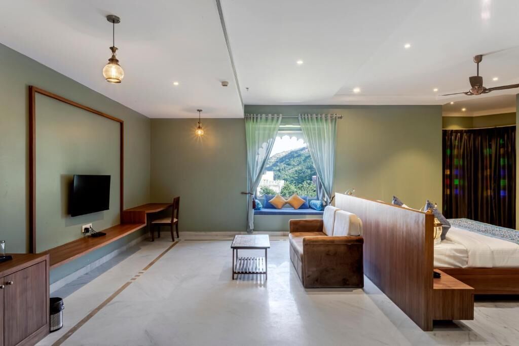 Une chambre d’hôtel moderne avec un grand lit, un canapé, une télévision et une fenêtre avec des rideaux.