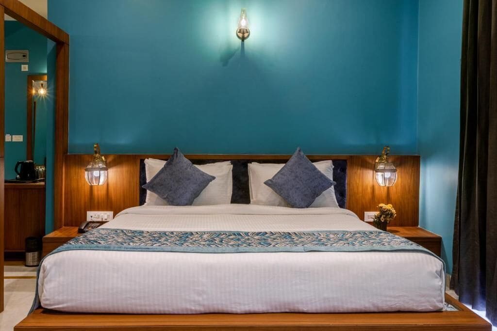 A neatly made bed with a patterned bedspread, two wall-mounted lamps, and a wooden headboard.