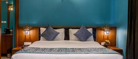 A neatly made bed with a patterned bedspread, two wall-mounted lamps, and a wooden headboard.