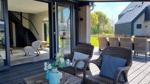 A covered outdoor seating area with wicker furniture and a table with a vase of flowers.