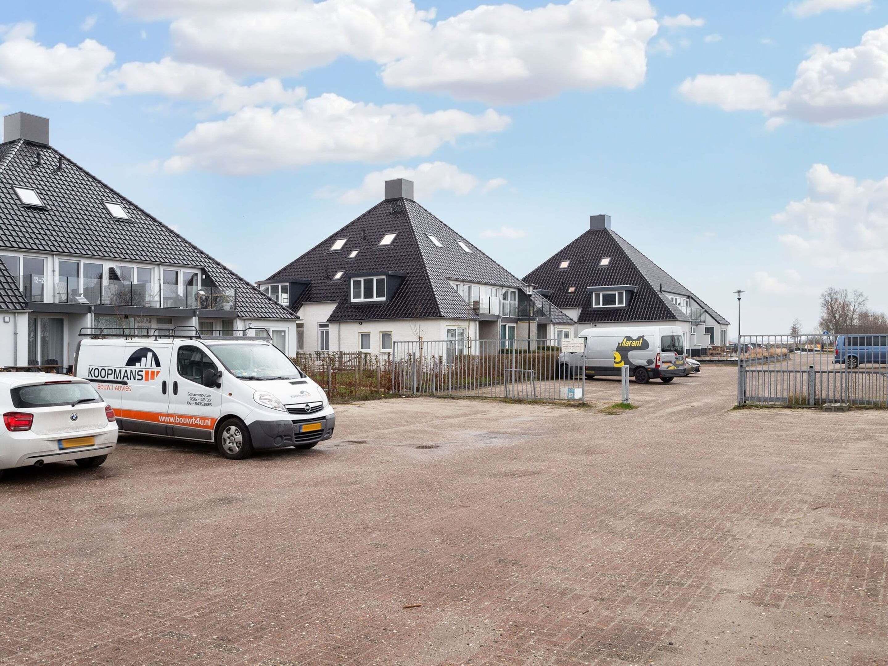 Un quartier résidentiel avec des maisons, une allée gravillonnée et des voitures garées.