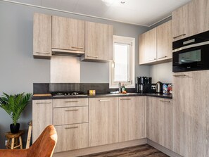 A modern kitchen with light wood cabinets, a gas stove, a coffee maker, and a microwave. - Nice Holiday Home With Boat and Jetty (Bantega)