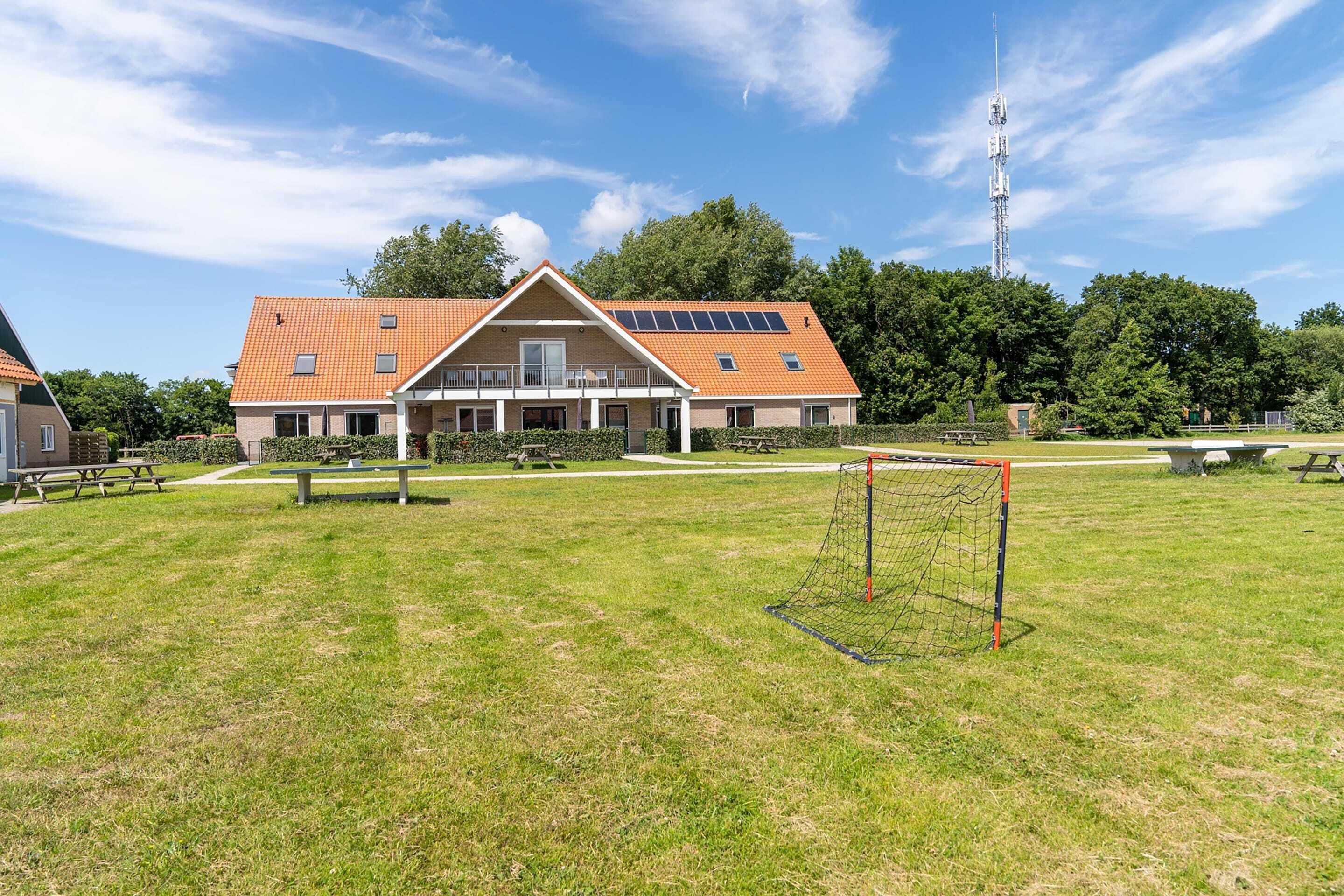 Ein Wohngebäude mit einem geneigten Dach, Solaranlagen und einer großen Rasenfläche mit einem Fußballtor.