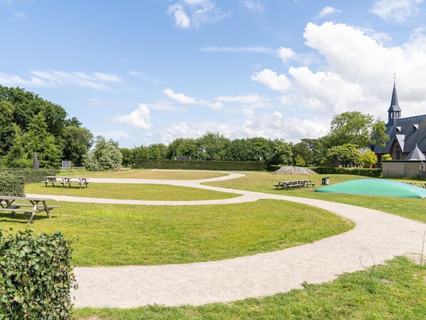 A park with picnic tables, a winding path, and a church with a steeple.