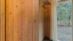 A wooden interior hallway with a door and a view of an outdoor area with trees and a path.