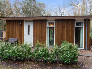 Una casa moderna de madera con puerta, ventana y un banco.